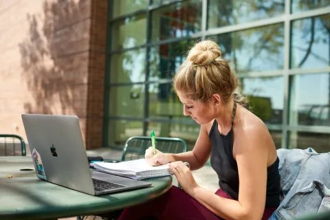 Student working on computer and taking notes