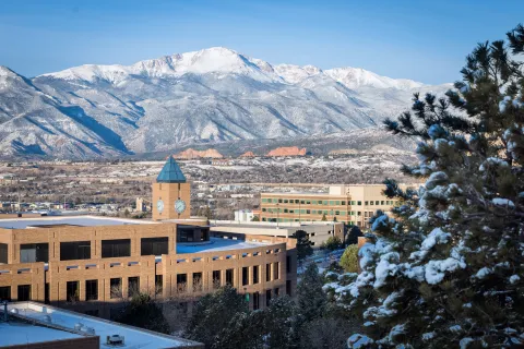 Snow covered UCCS building with mountain backdrop 